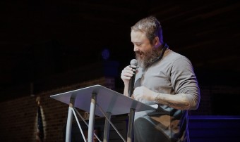 a bearded man preaching behind a pulpit