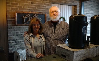 a man and a woman stand behind a coffee booth