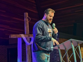 a bearded man preaching from a pulpit