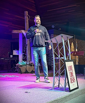 a bearded man preaching from the pulpit